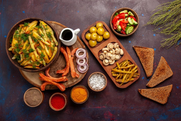 Vista superior de papas fritas con panes de pan de condimentos y diferentes verduras en la superficie oscura