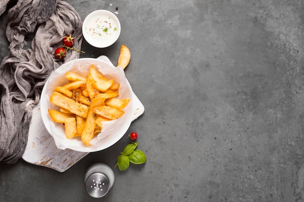 Vista superior de papas fritas en un plato con salero y espacio de copia