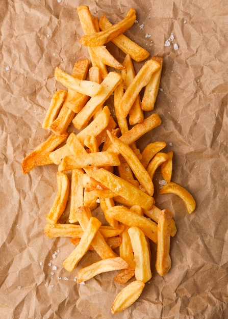 Vista superior de papas fritas con sal sobre papel
