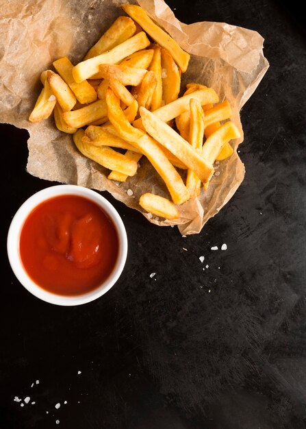 Vista superior de papas fritas saladas con salsa de tomate