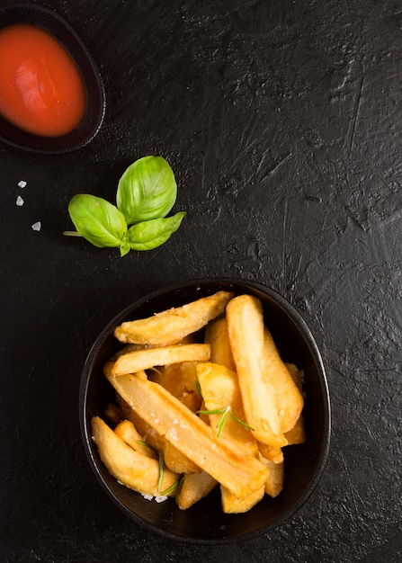 Vista superior de papas fritas con salsa de tomate y sal