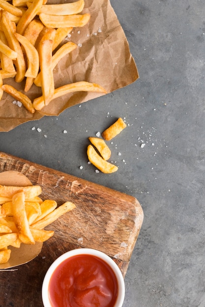 Vista superior de papas fritas con salsa de tomate y sal