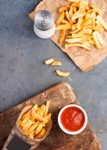 Vista superior de papas fritas con salsa de tomate y salero