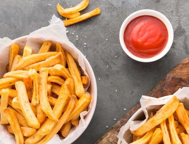 Vista superior de papas fritas en un tazón con salsa de tomate