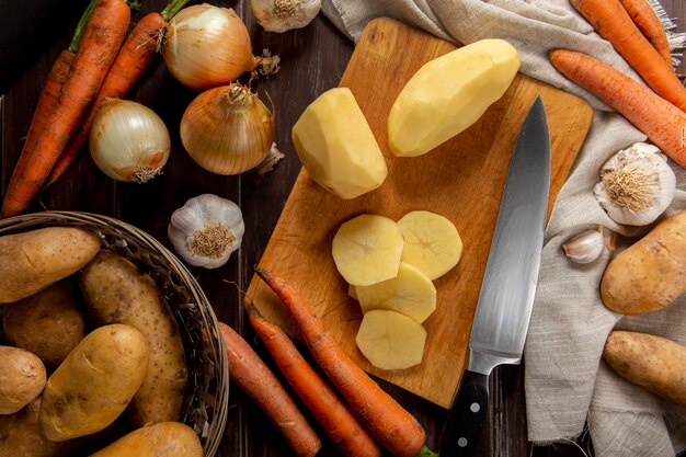 Vista superior de papas peladas con ajo y cebolla