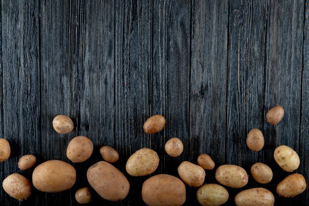 Vista superior de papas pequeñas y grandes sobre fondo de madera con espacio de copia 2