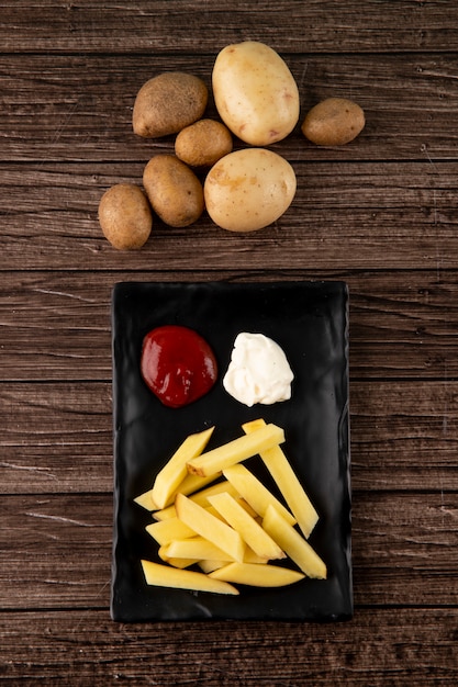 Foto gratuita vista superior de papas con salsa de tomate y mayonesa sobre fondo de madera