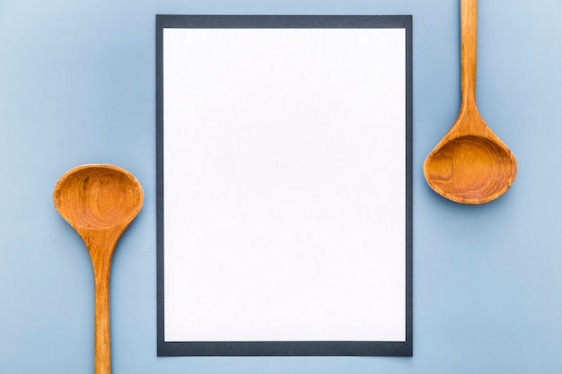 Vista superior del papel de menú en blanco con cucharas de madera