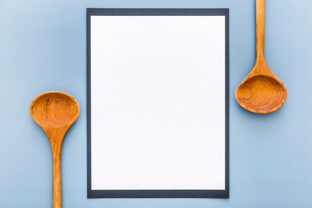 Vista superior del papel de menú en blanco con cucharas de madera