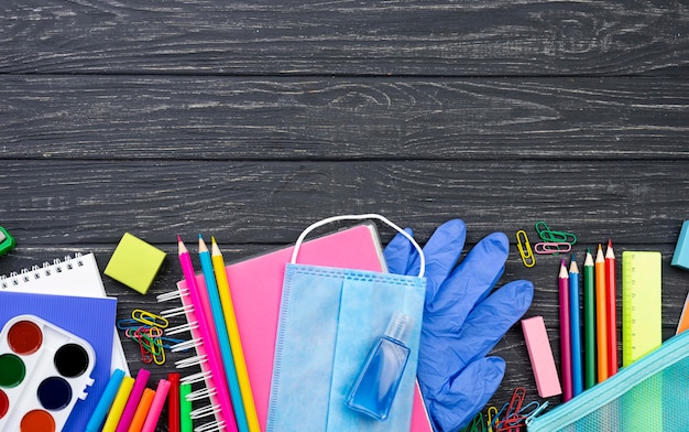 Vista superior de papelería de regreso a la escuela con lápices multicolores y máscara médica