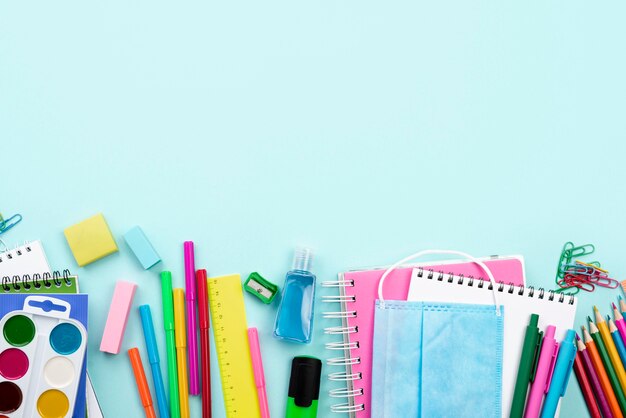 Vista superior de papelería de regreso a la escuela con máscara médica y lápices de colores