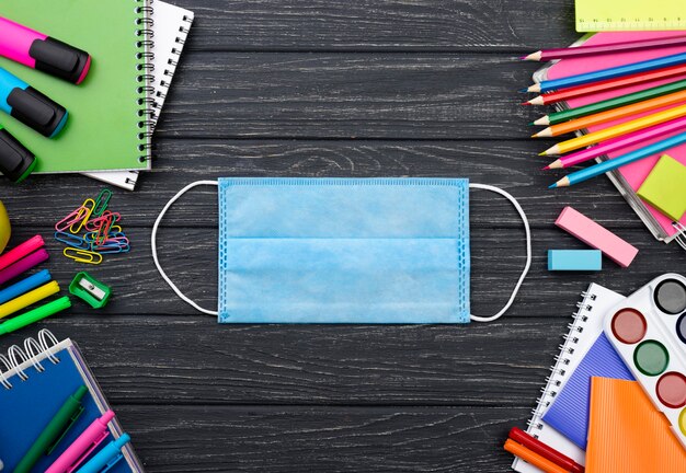 Vista superior de papelería de regreso a la escuela con mascarilla y lápices de colores