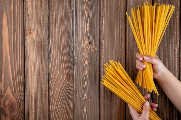 Vista superior de pasta bucatini a la derecha con espacio de copia sobre fondo de madera