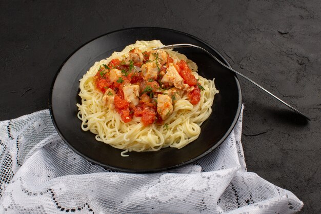 Vista superior pasta cocinada con alitas de pollo y salsa de tomate dentro de un plato negro o oscuro