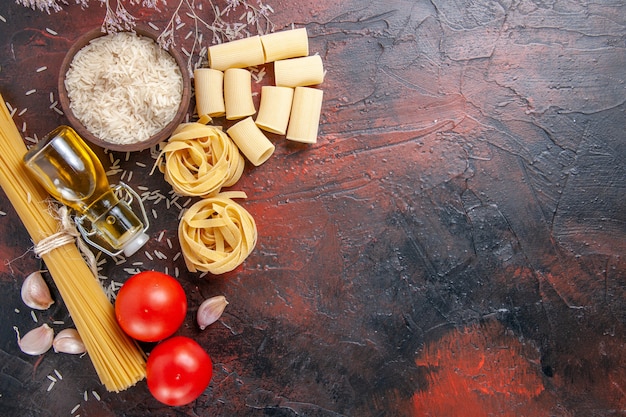 Foto gratuita vista superior de pasta cruda con arroz y tomates en la superficie oscura pasta de masa cruda