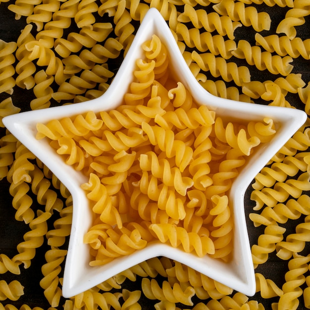 Vista superior de pasta cruda en roseta en forma de estrella sobre superficie de madera