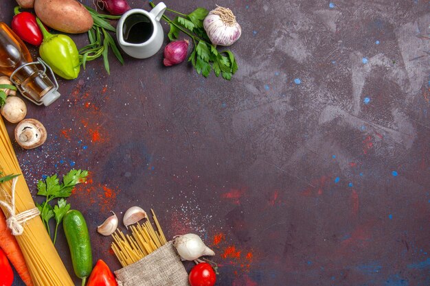 Vista superior de pasta cruda con verduras frescas en la comida de ensalada de comida de escritorio oscuro