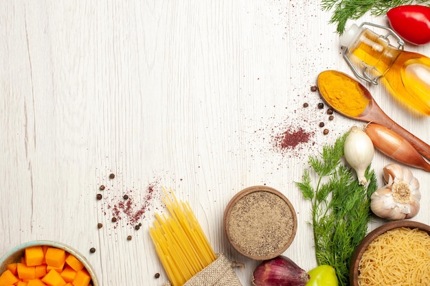 Foto gratuita vista superior de pasta cruda con verduras y verduras en el cuadro blanco