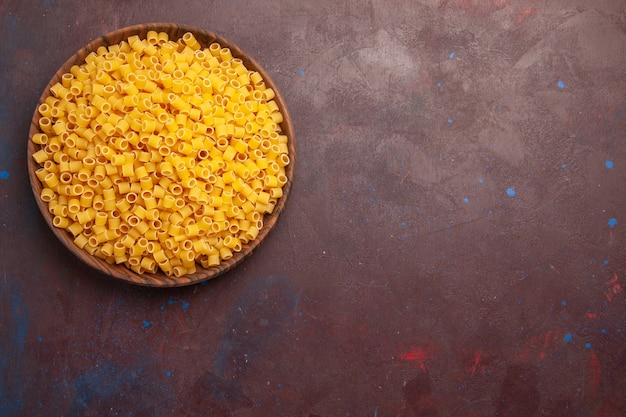 Vista superior de pasta italiana amarilla cruda poco formada en el escritorio oscuro pasta comida cruda masa de harina