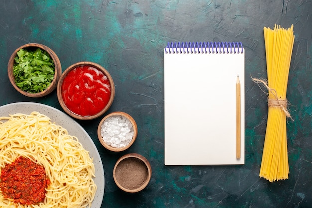 Foto gratuita vista superior de pasta italiana cocida con carne y diferentes condimentos en el escritorio azul oscuro