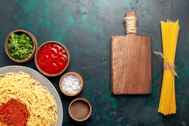 Vista superior de pasta italiana cocida con carne y diferentes condimentos en la superficie azul oscuro