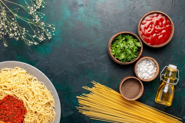 Vista superior de pasta italiana cocida con carne y diferentes condimentos en la superficie azul oscuro