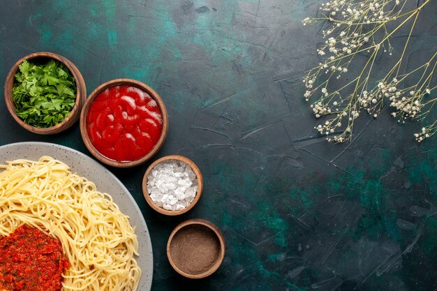 Vista superior de pasta italiana cocida con carne y diferentes condimentos en la superficie azul oscuro