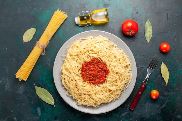 Foto gratuita vista superior de pasta italiana cocida con carne de tomate picada en el escritorio azul oscuro