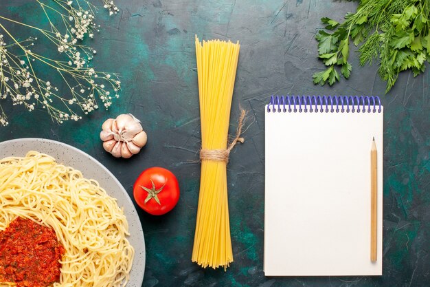 Vista superior de pasta italiana cocida con salsa de tomate carne picada en la superficie azul