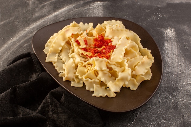 Una vista superior de pasta italiana cocida con salsa de tomate dentro de la placa oscura