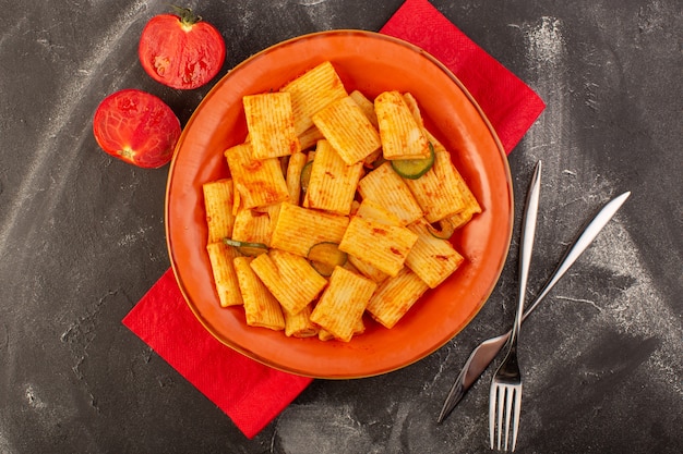 Una vista superior de pasta italiana cocida con salsa de tomate y pepino dentro de la placa