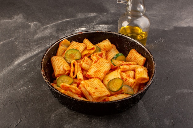 Una vista superior de pasta italiana cocida con salsa de tomate y pepino dentro de la sartén sobre la mesa oscura comida plato de pasta italiana