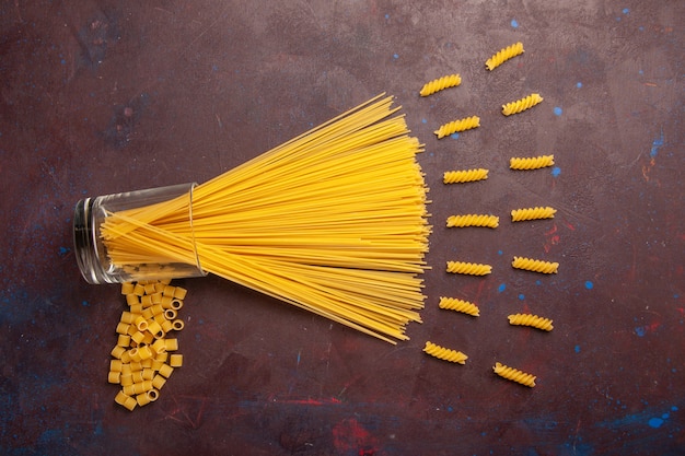 Foto gratuita vista superior de pasta italiana cruda formada largamente de color amarillo sobre fondo violeta oscuro pasta pasta italiana comida color crudo