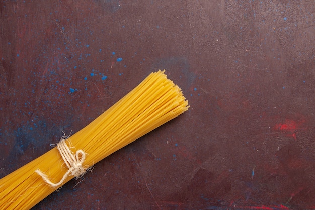 Vista superior de la pasta italiana cruda formada durante mucho tiempo sobre el fondo de color púrpura oscuro, comida, masa, pasta cruda