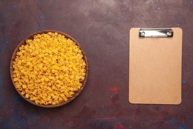 Vista superior de pasta italiana cruda poco formada dentro de la placa sobre fondo oscuro comida de pasta masa de alimentos muchos