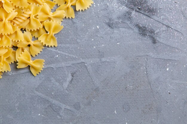 Una vista superior de pasta italiana cruda poco formada en el escritorio gris pasta comida italiana