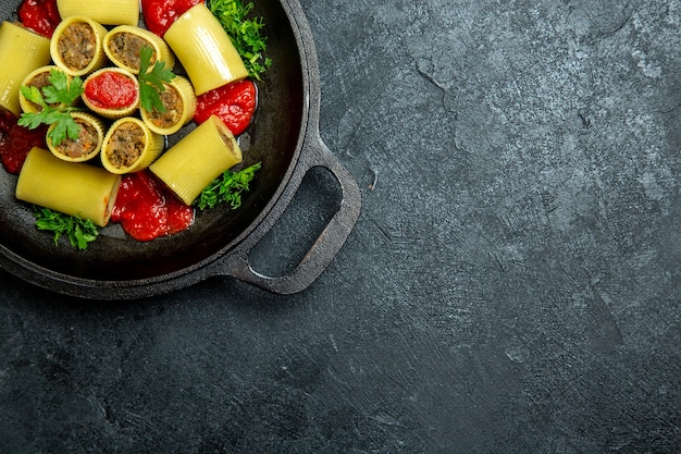 Vista superior de pasta italiana cruda con verduras de carne y salsa de tomate dentro de la sartén en el fondo oscuro comida de masa de pasta