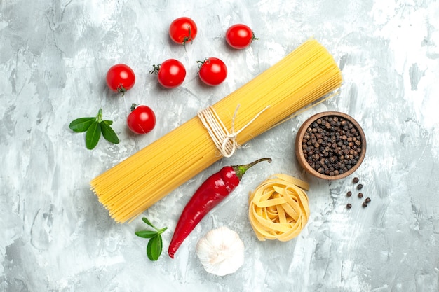 Vista superior de pasta italiana larga con tomates rojos frescos sobre fondo blanco.