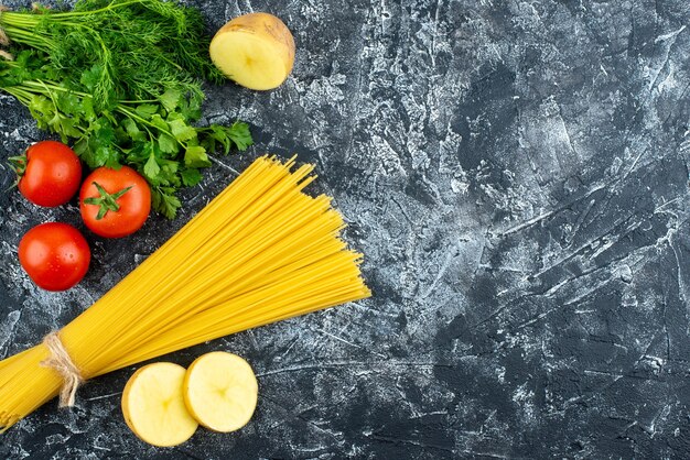 Vista superior de pasta larga cruda con verduras y tomates sobre fondo gris claro masa de pasta de cocina cocina de alimentos cocina de color