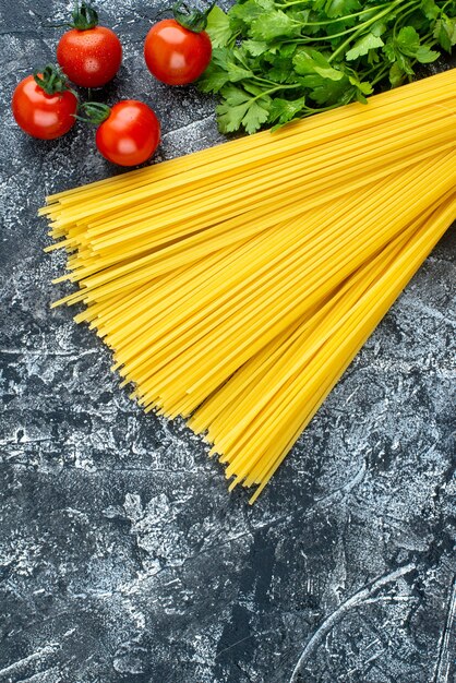 Vista superior de pasta larga cruda con verduras y tomates sobre fondo gris cocina de color masa de pasta comida cocina cocina cocina