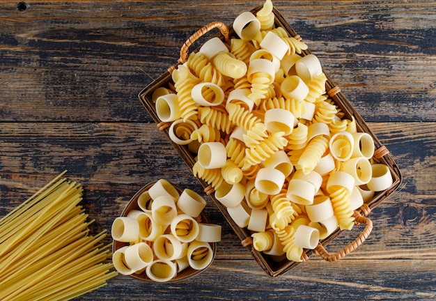Vista superior de pasta de macarrones en la cesta con espagueti sobre fondo de madera. horizontal