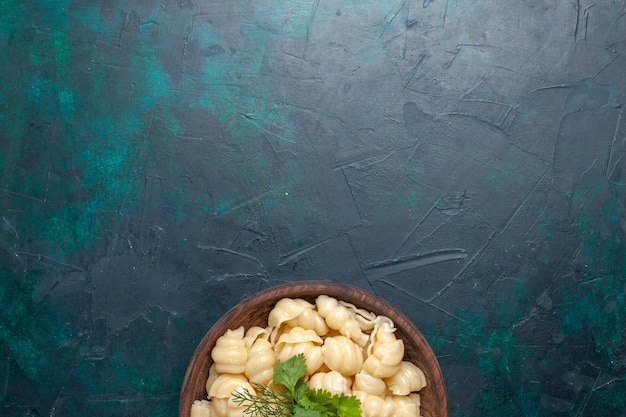 Vista superior de pasta de masa cocida con verduras dentro de la placa en el escritorio oscuro