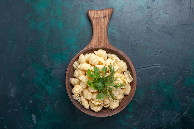 Foto gratuita vista superior de la pasta de masa cocida con verduras dentro de la placa sobre la superficie oscura