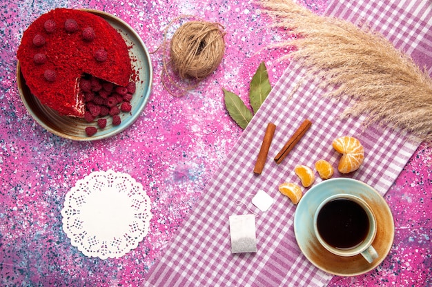 Vista superior del pastel de frambuesa roja con canela, mandarinas y té en la superficie rosa