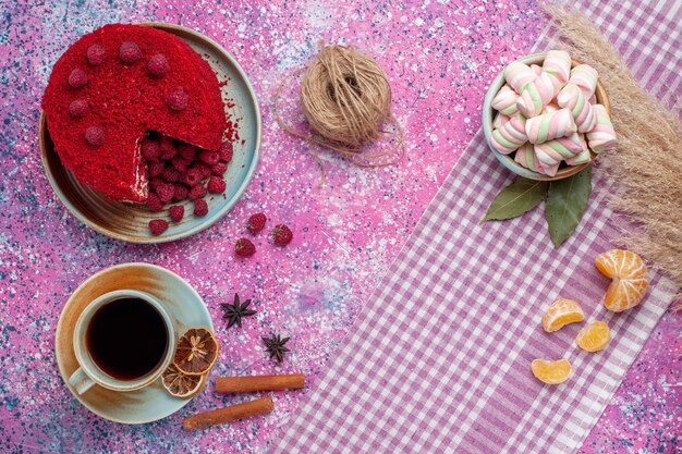 Vista superior del pastel de frambuesa roja con canela y té en la superficie rosa