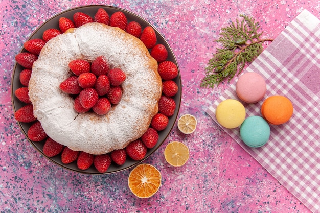 Vista superior pastel de fresa pastel de azúcar en polvo con macarons en el rosa