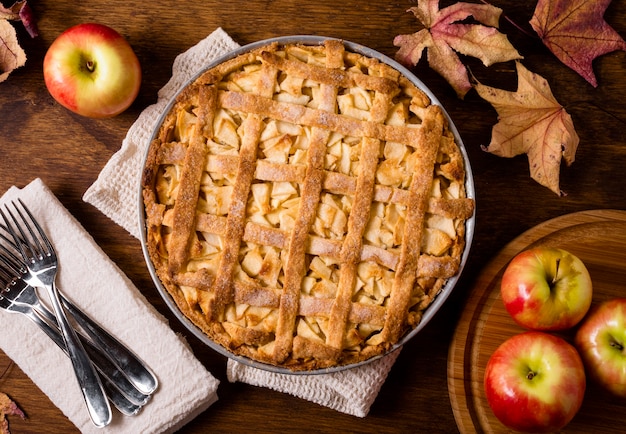 Vista superior del pastel de manzana para acción de gracias con cubiertos y hojas