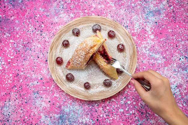 Vista superior de pastelería de cereza deliciosa y dulce en rodajas con guindas frescas dentro de la placa en el escritorio de color pastel galleta azúcar dulce hornear