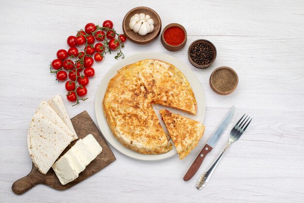 Vista superior de pastelería vegetal cocida redonda dentro de la placa blanca junto con queso blanco y tomates escritorio comida comida pastelería almuerzos verdes