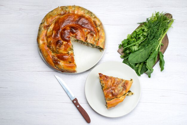 Vista superior de pastelería de verduras cocidas en rodajas dentro de las placas con verduras frescas en el escritorio de madera marrón, comida, pastelería, cena verde